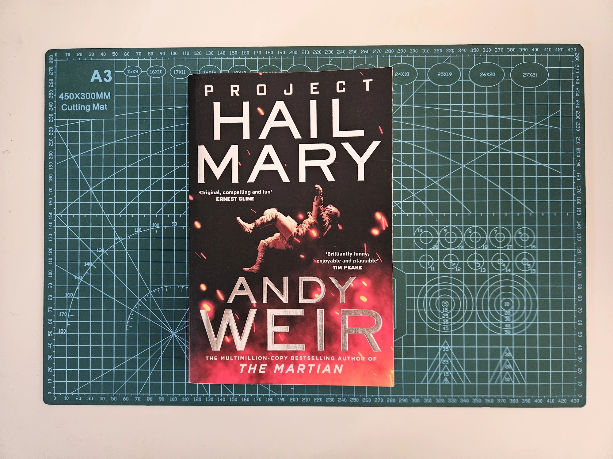 Top-view of my paperback copy of Project Hail Mary (cutting-mat for scale)